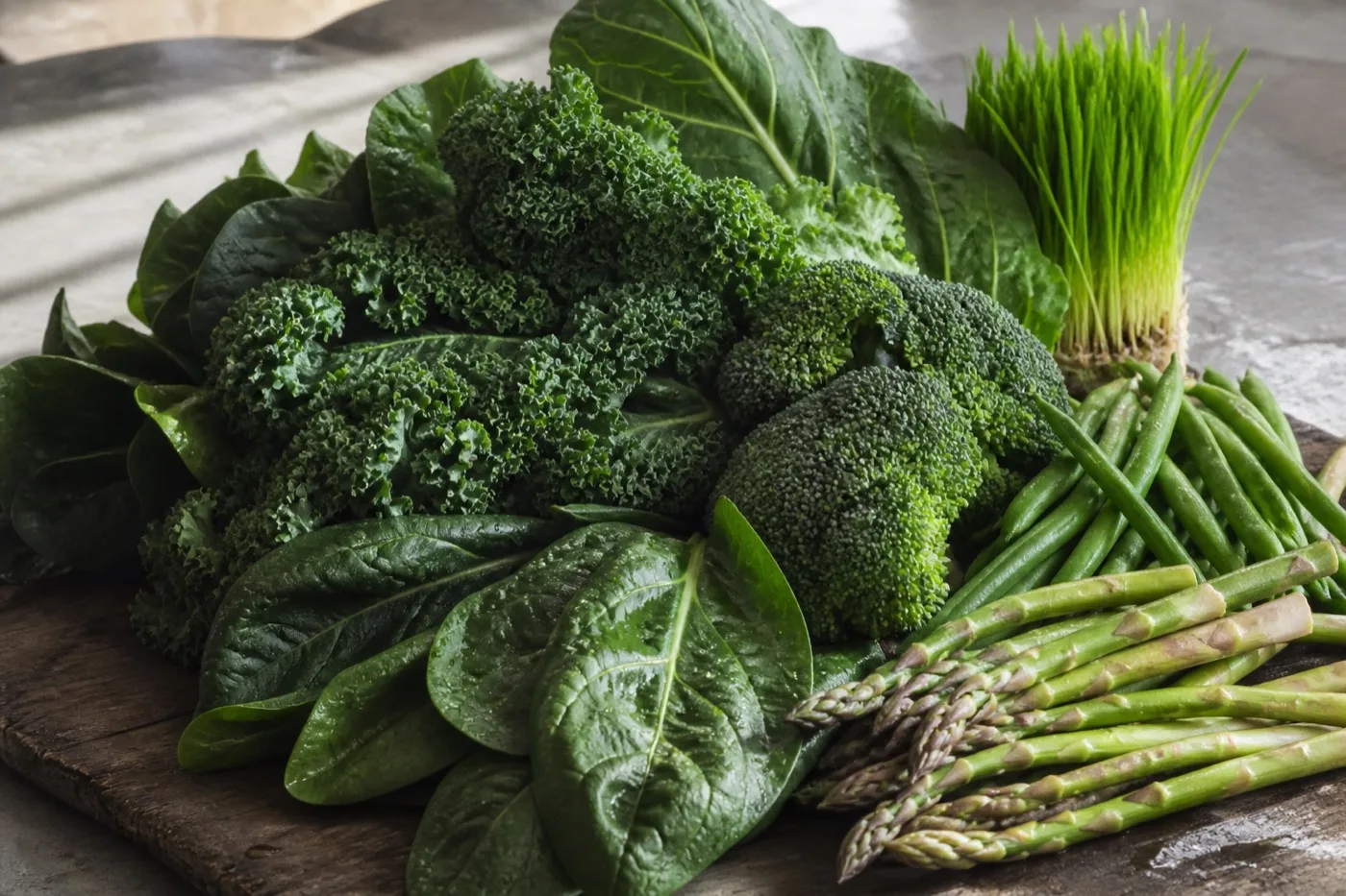 Spinach, kale, broccoli, green beans, asparagus and a bunch of wheatgrass on a stone counter
