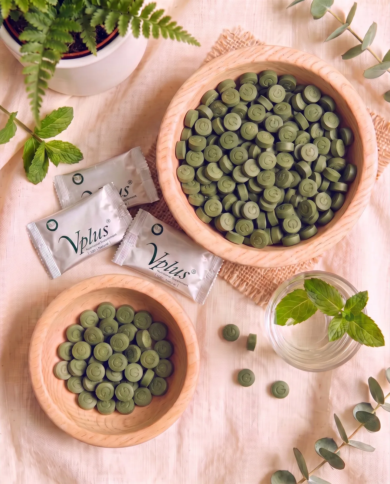 Two wooden bowls of Vplus tablets with sachets, mint and eucalyptus, seen from above